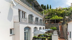 A building with a balcony, outdoor seating, and a staircase. - Residence Le Villette (Ravello)