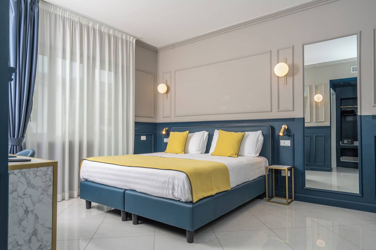 Un dormitorio moderno con cama, mesitas de noche, un espejo y un armario.