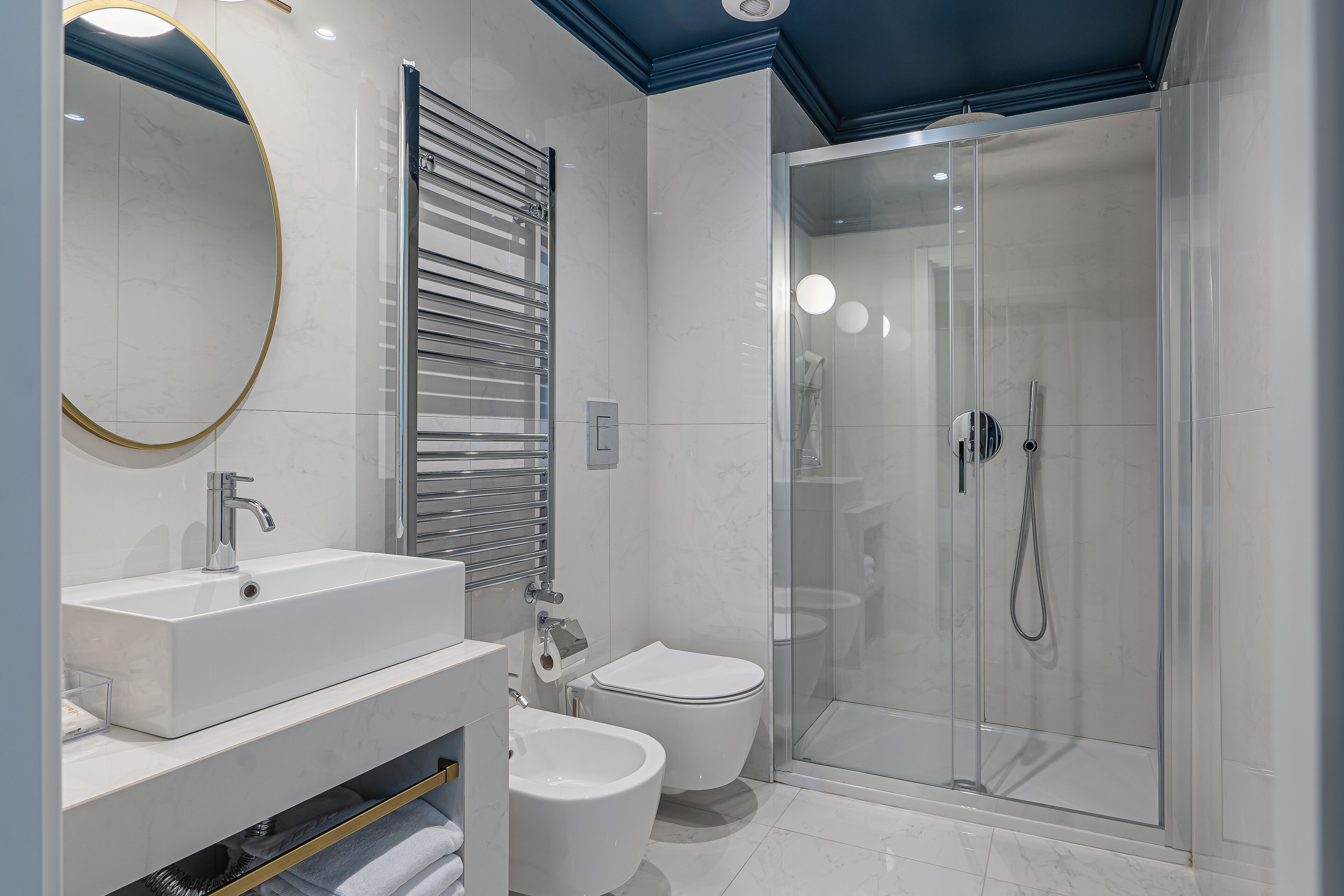 A modern bathroom with a large sink, toilet, bidet, and glass-enclosed shower.
