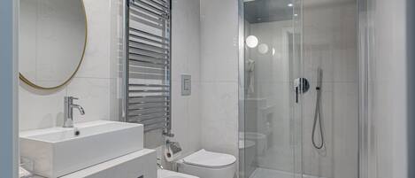 Un baño moderno con lavamanos grande, inodoro, bidé y ducha con mampara de vidrio.