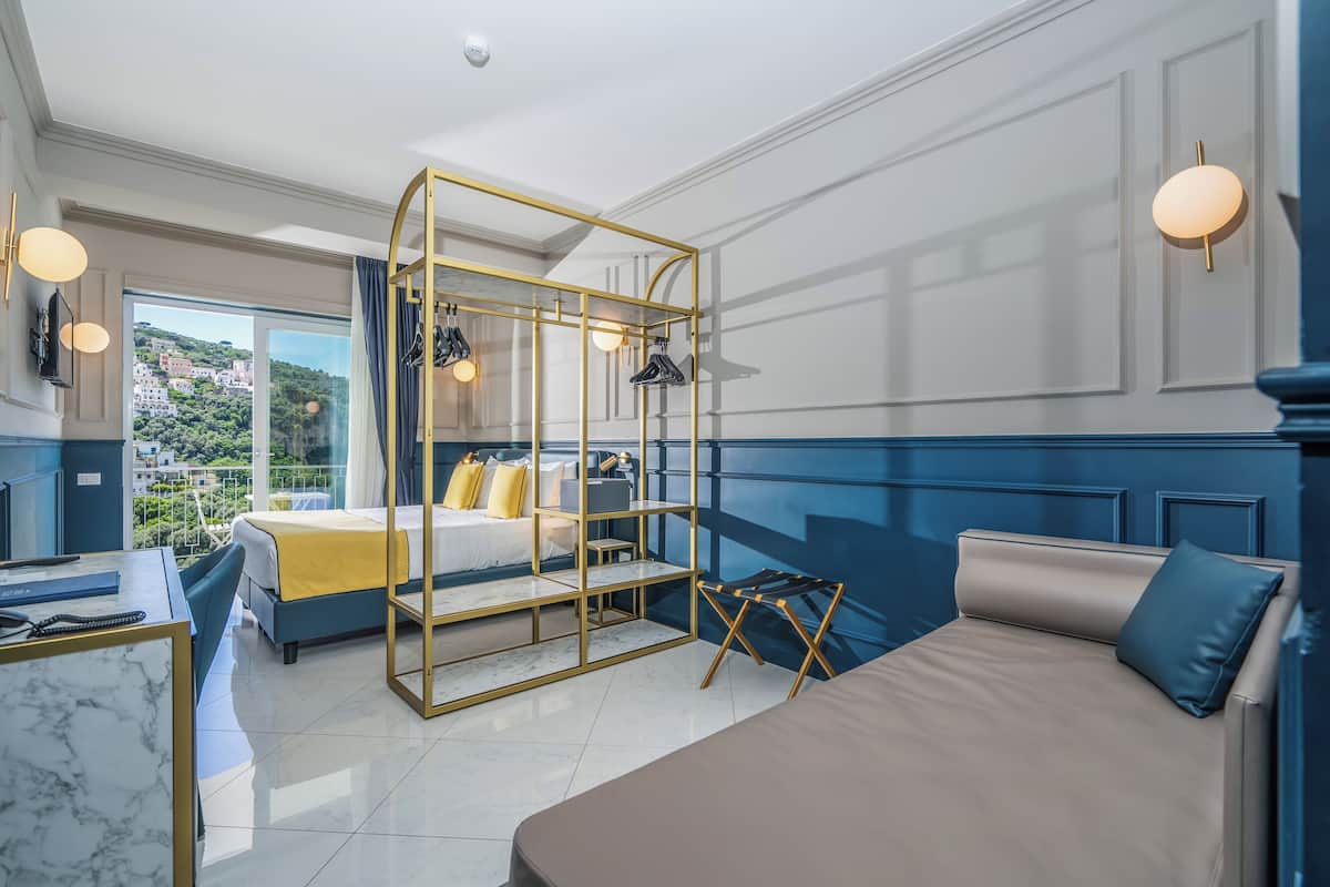 Una habitación de hotel moderna con una cama grande, un escritorio, un balcón con vistas y un separador de vidrio original.