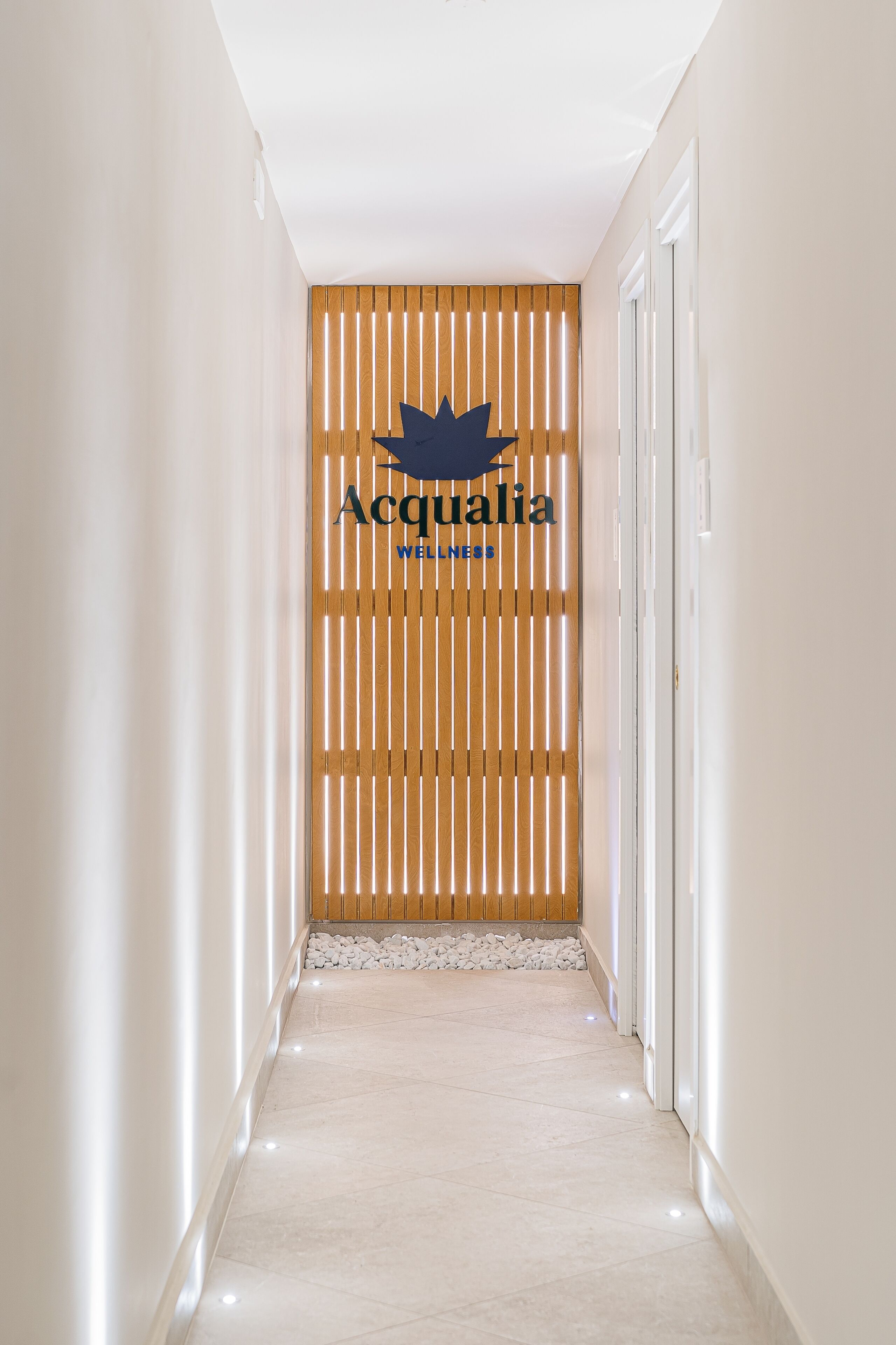 A hallway with a wooden slat wall, a logo, and a tiled floor.