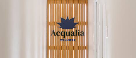 A hallway with a wooden slat wall, a logo, and a tiled floor.