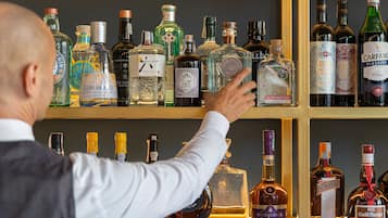 Un hombre elige una botella de un estante lleno de diferentes licores.
