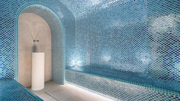 Bathroom features a large, white column and blue mosaic tile design.