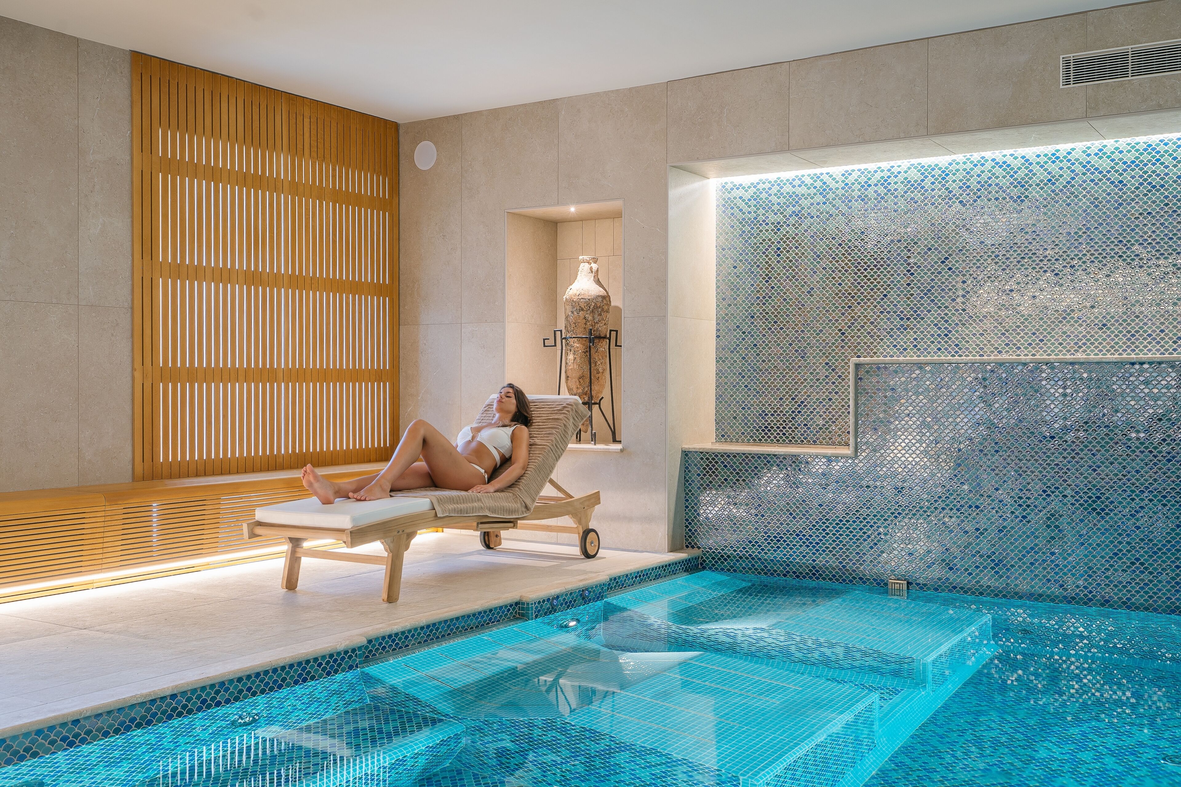 A spa area with a pool, wooden slats, and a tiled wall.