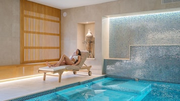 Ein Wellnessbereich mit Pool, Holzlamellen und einer gefliesten Wand.