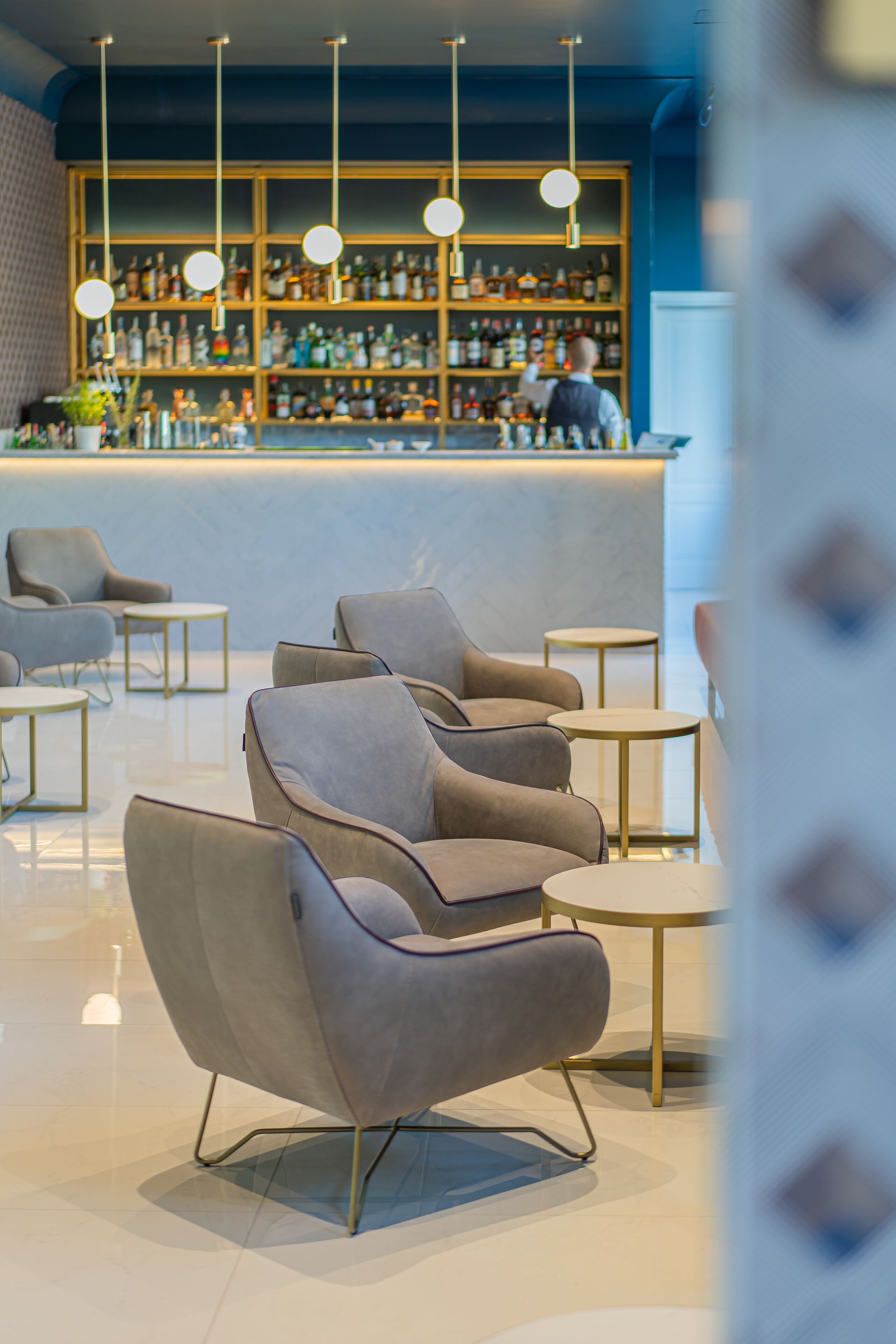 Zona de bar moderna con asientos y una estantería repleta de licores.