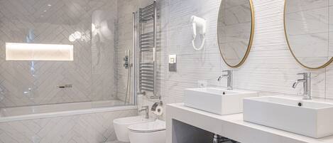A modern bathroom with a freestanding bathtub, two sinks, a toilet, and a large mirror with a gold frame.