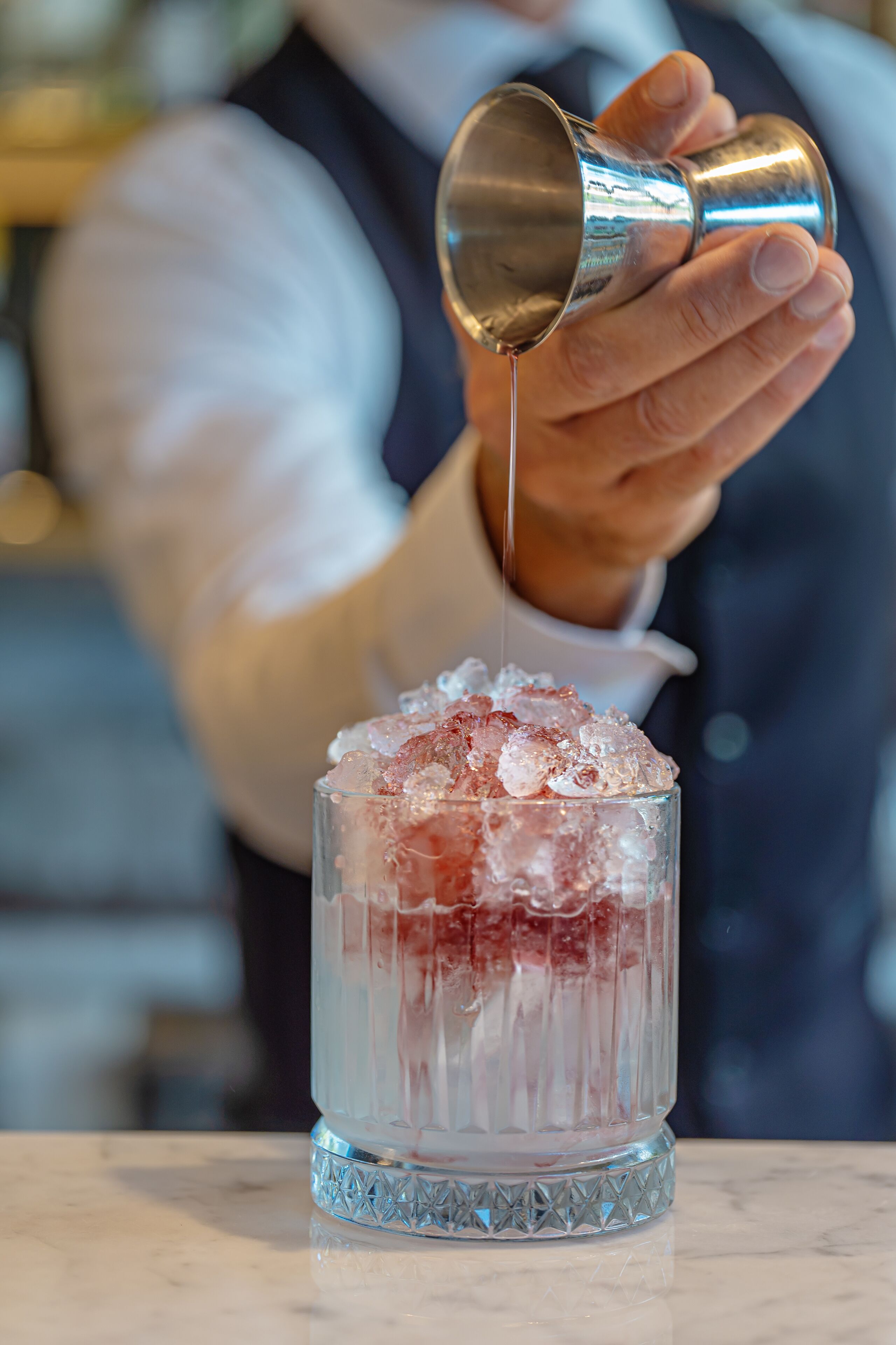 En bartender som häller upp en drink i ett glas med is.