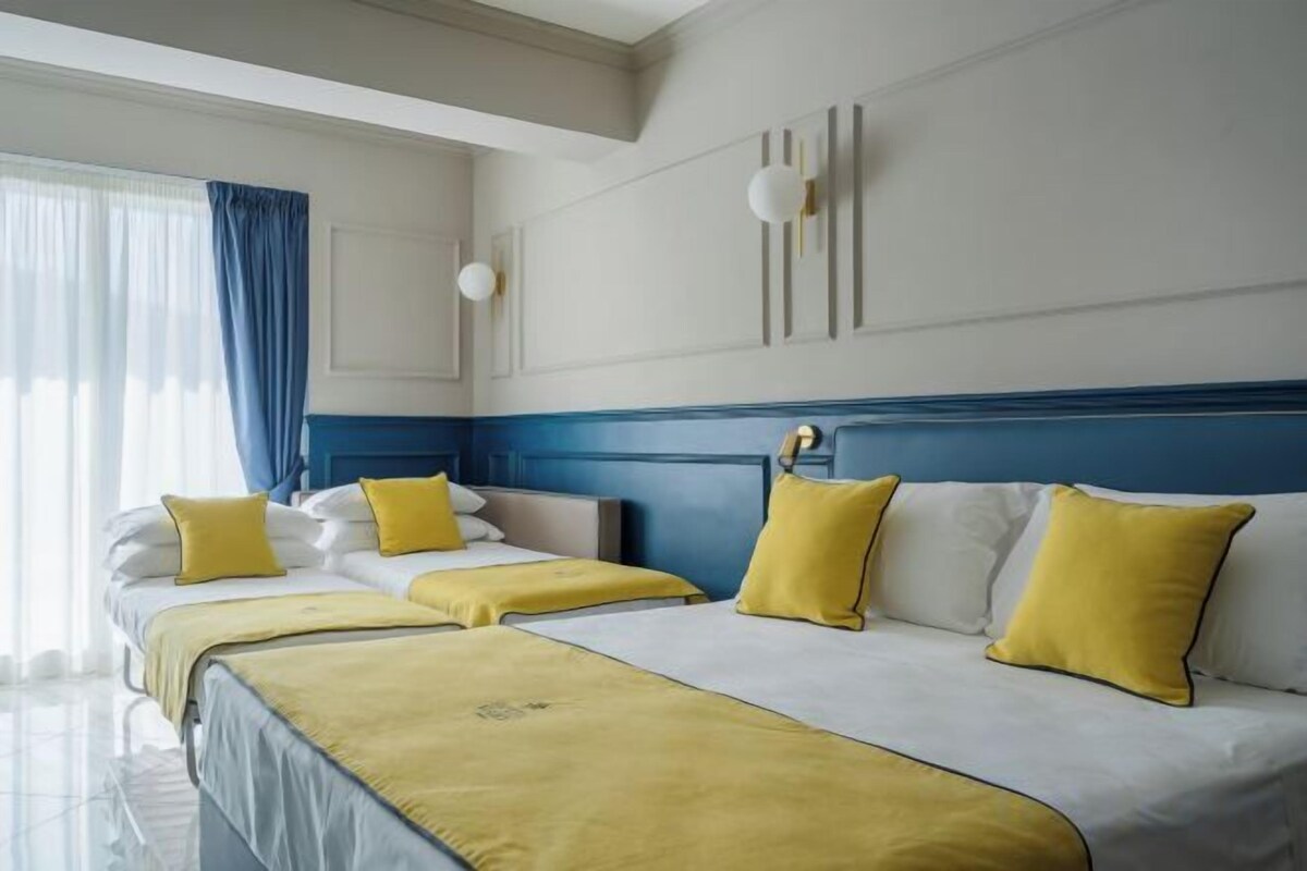 Une chambre d’hôtel avec un grand lit, un lit plus petit et un bureau.