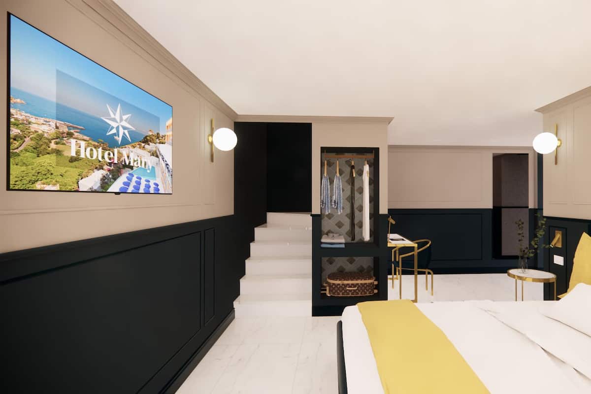 Habitación de hotel con cama, escritorio y ventana grande con vista al paisaje costero.