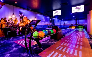 Een bowlinghal met een zeethematische achtergrond, een bollenrek en een bowlingbaan.