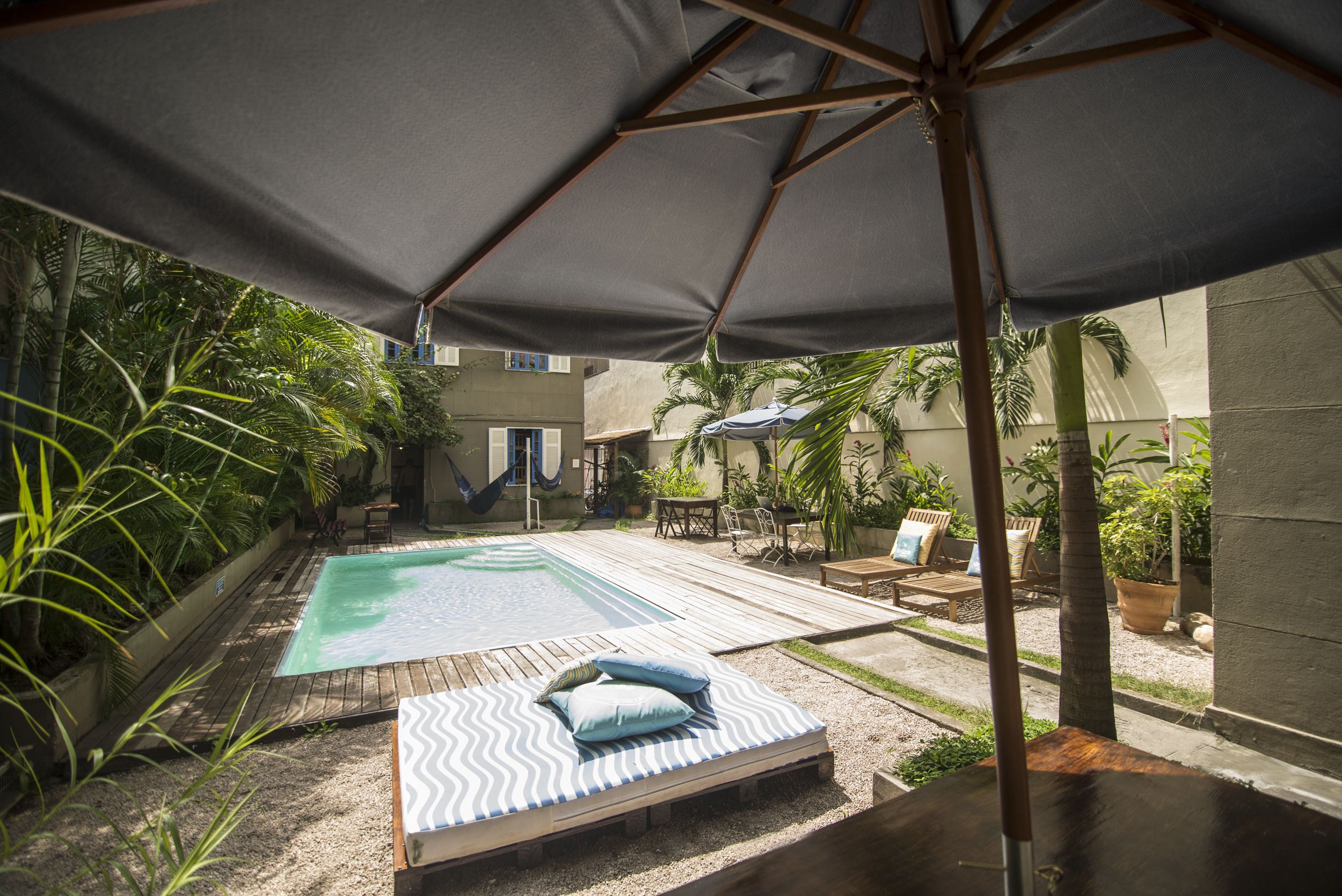 Een achtertuin met een zwembad, een houten terras en een loungehoek met een hangmat.