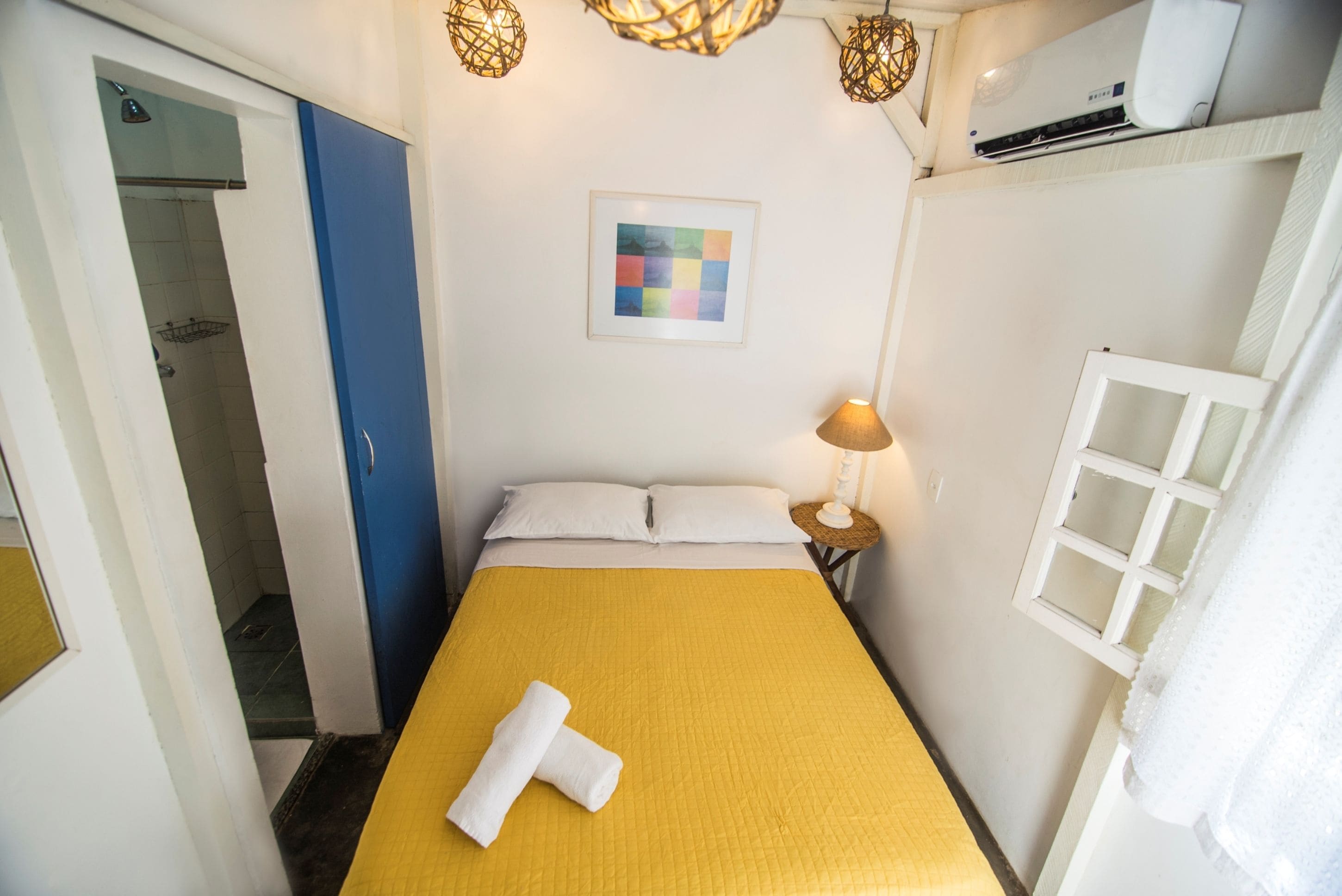 Une chambre d’hôtel avec un lit, une lampe de chevet, un tableau encadré et une fenêtre avec des rideaux.