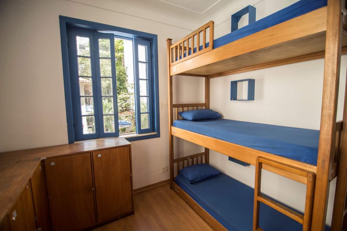 Quarto com beliche, escrivaninha de madeira e armários.