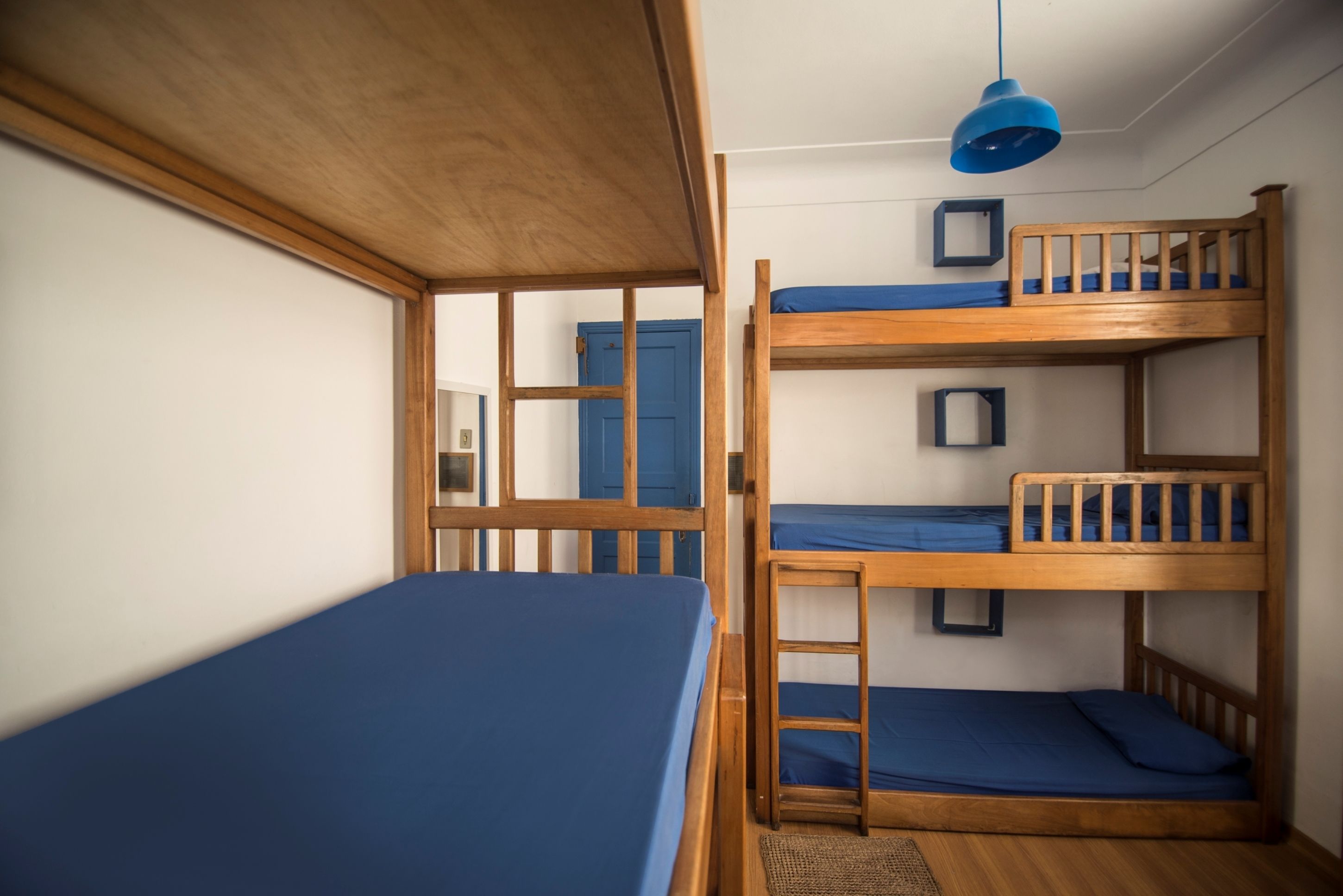 Dormitorio con literas, techo de madera y lámpara colgante azul.