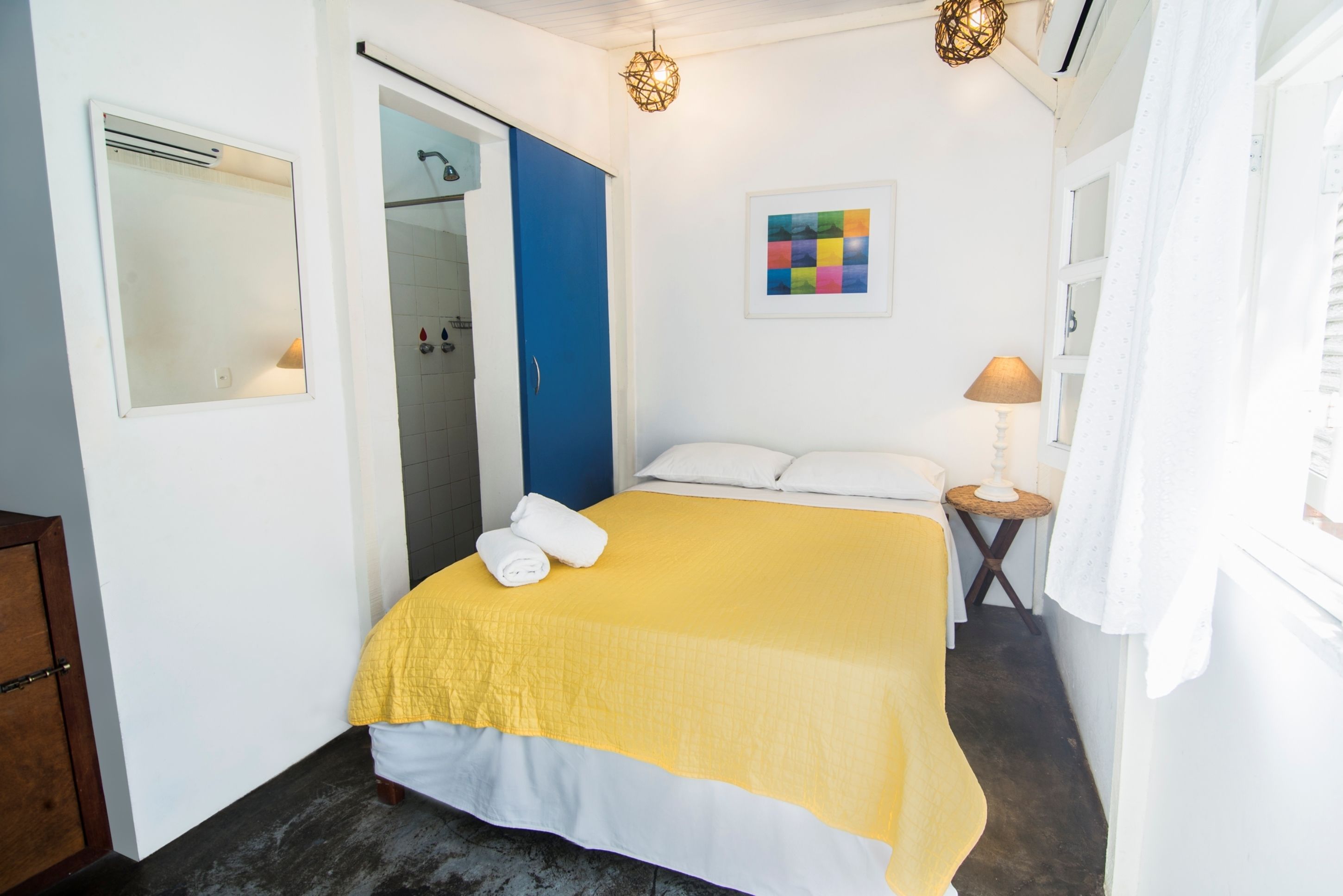 Une chambre d’hôtel comprenant un lit, une salle de bain, une petite table avec une lampe et une œuvre d’art accrochée au mur.
