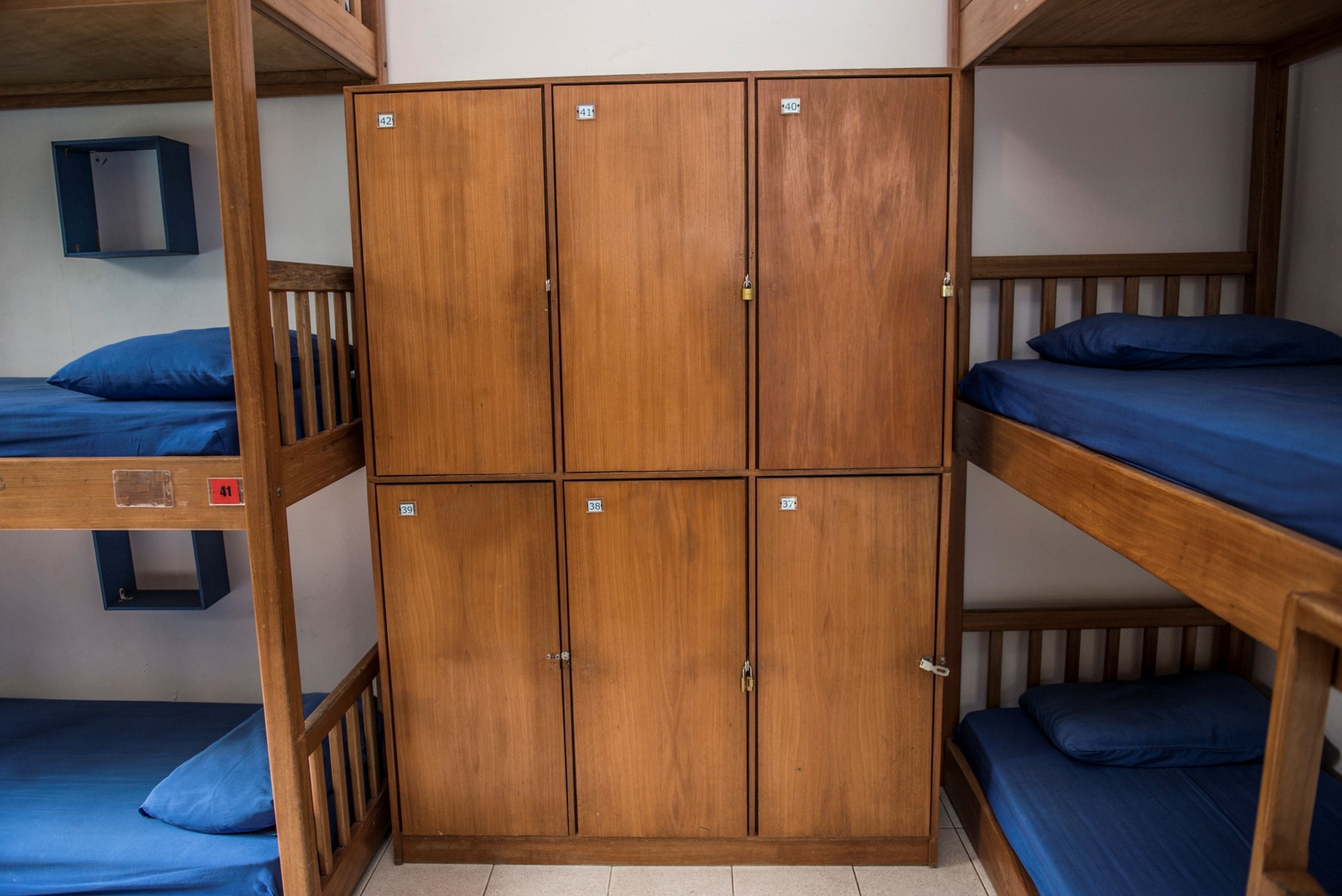 Camera con letto a castello in legno e un'ampia armadiatura centrale con scomparti multipli.