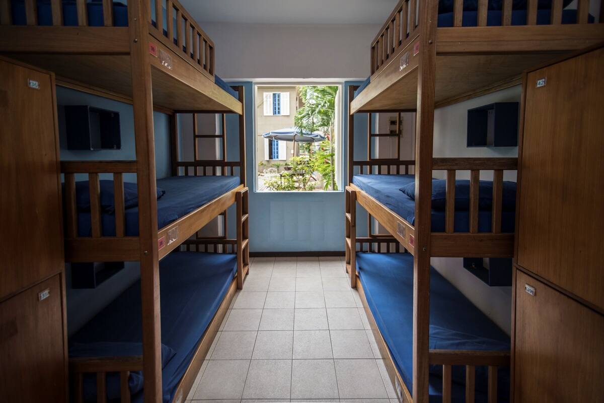 Um dormitório com beliches, janela com vista para o exterior e piso ladrilhado.