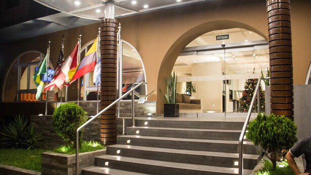 A hotel entrance with a staircase leading to the lobby, multiple flags, and a sign reading "ENTRADA". - Best Western Trujillo (Trujillo)