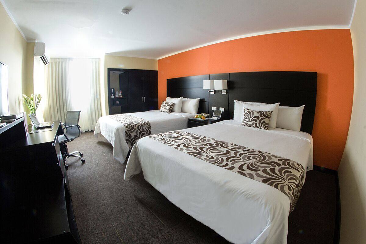 A hotel room with two beds, a desk, and a chair.