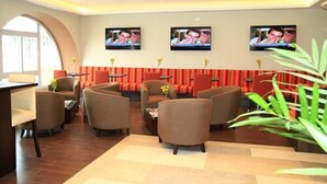 A hotel lobby with multiple seating areas, a reception desk, and three televisions mounted on the wall. - Best Western Trujillo (Trujillo)