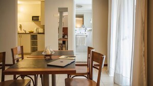 A dining area with a table and chairs, a kitchen in the background, and a bathroom visible through an open door. - Donsuites Apart Hotel (Corrientes)