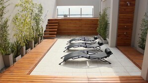 A rooftop terrace with a wooden deck, outdoor seating, and potted plants. - Donsuites Apart Hotel (Corrientes)