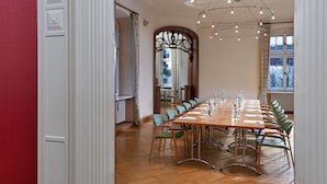 Un salón de conferencias con una larga mesa, sillas y una araña.