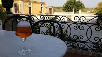Una cerveza en una mesa redonda con una valla de hierro forjado al fondo.