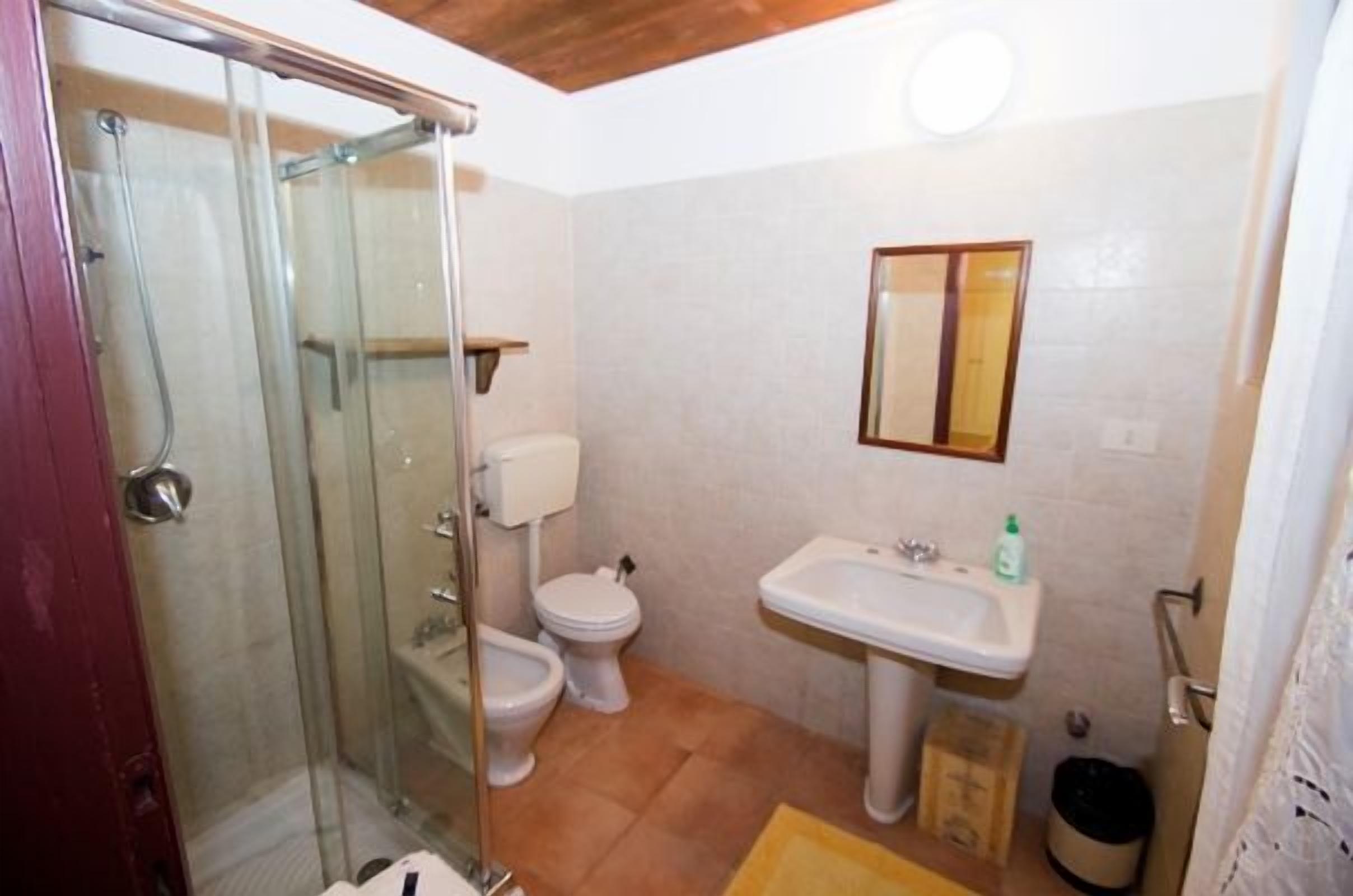 Ein Badezimmer mit Duschkabine, Toilette, Waschbecken und Spiegel.