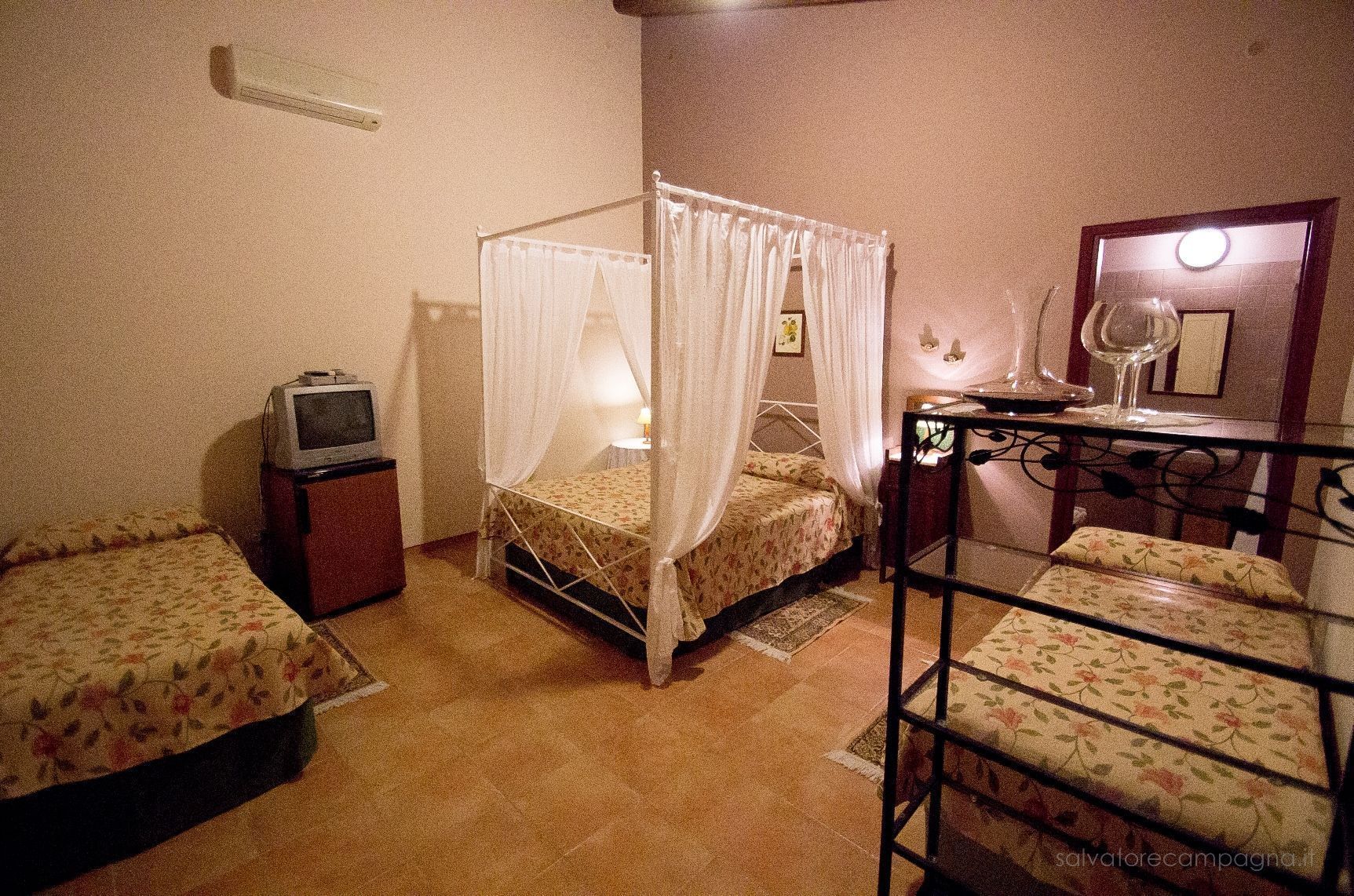 A small, cozy room with a single bed, a TV, and a bedside table.