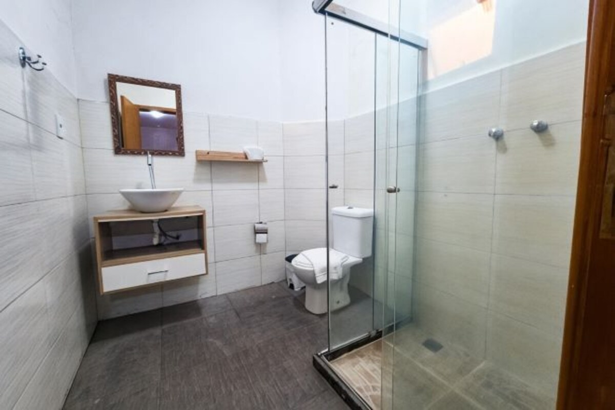 A bathroom with a glass shower enclosure, a white sink with a mirror, and a toilet.