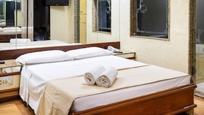 Une chambre d’hôtel comprenant un lit, une table de chevet, un miroir, une télévision et une fenêtre ornée de cadres décoratifs.