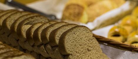 A loaf of sliced bread and a basket of pastries on a table.