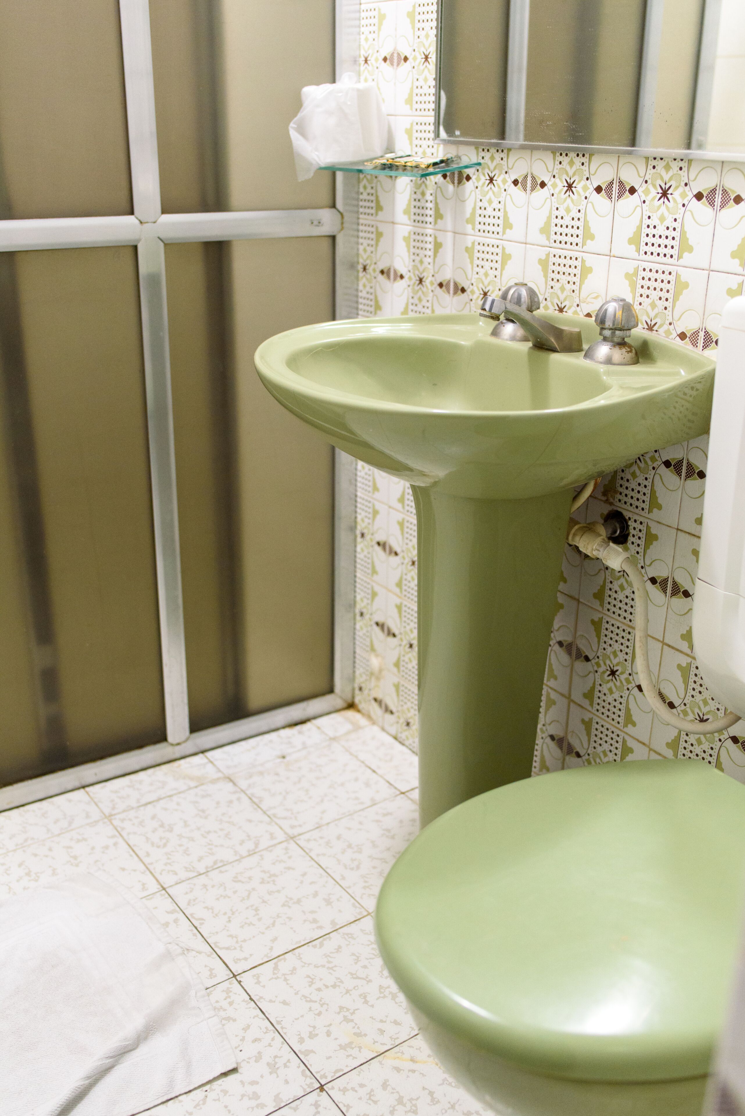 A bathroom with a green sink and a toilet.