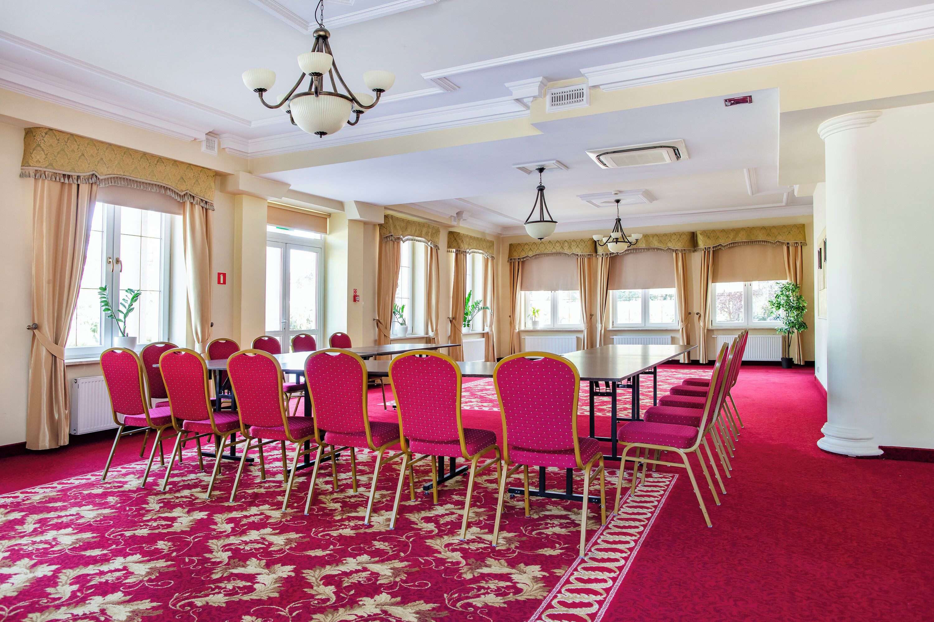 A conference room with a red carpet, beige walls, and a chandelier.