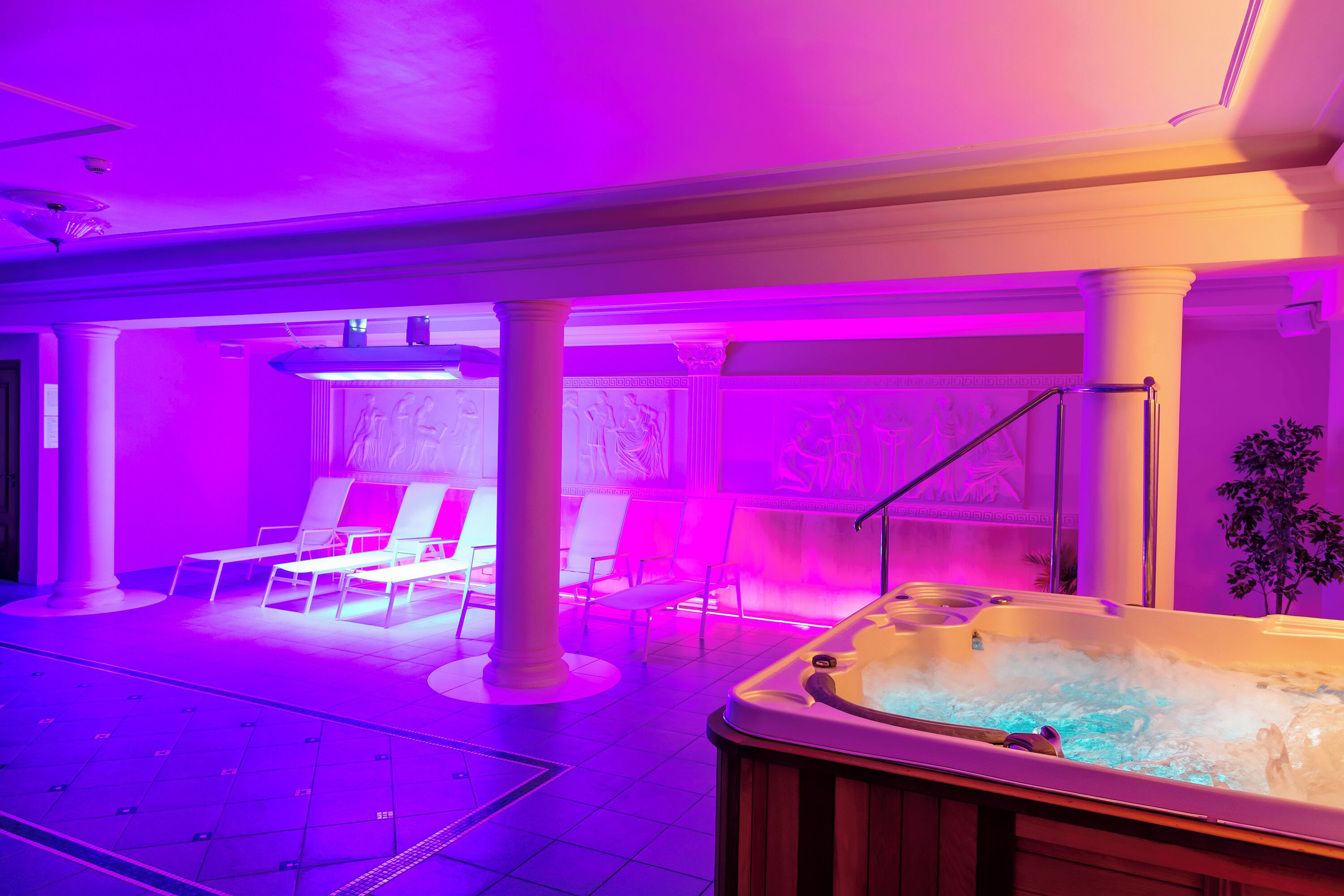 A spa area with a hot tub, lounge chairs, and a tiled floor.