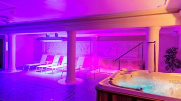 A spa area with a hot tub, lounge chairs, and a tiled floor.