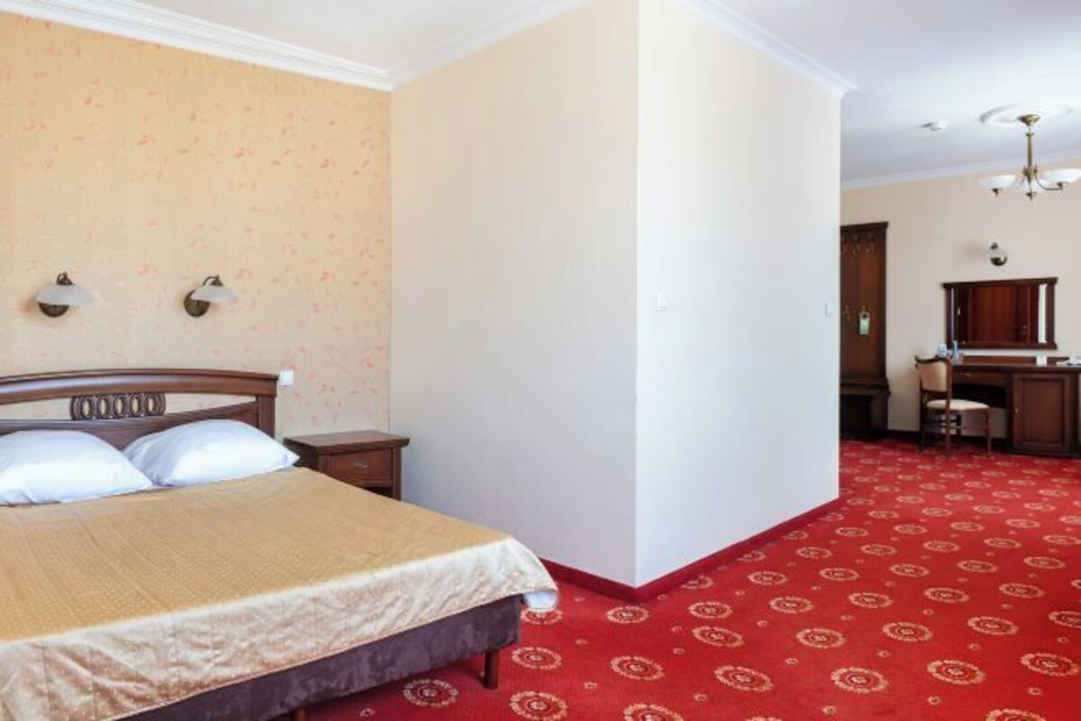 A hotel room with a bed, a desk, and a chair.