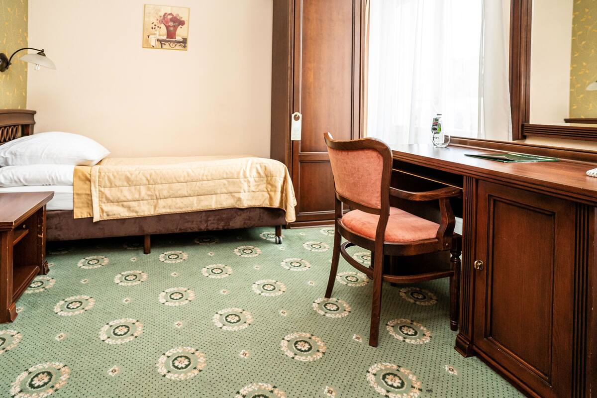 A room with a bed, a desk, a chair, and a cabinet.