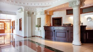 A reception area with a marble floor, a reception desk labeled "RECEPCIA," and a large mirror above it. - Anin Park Hotel (Warsaw)