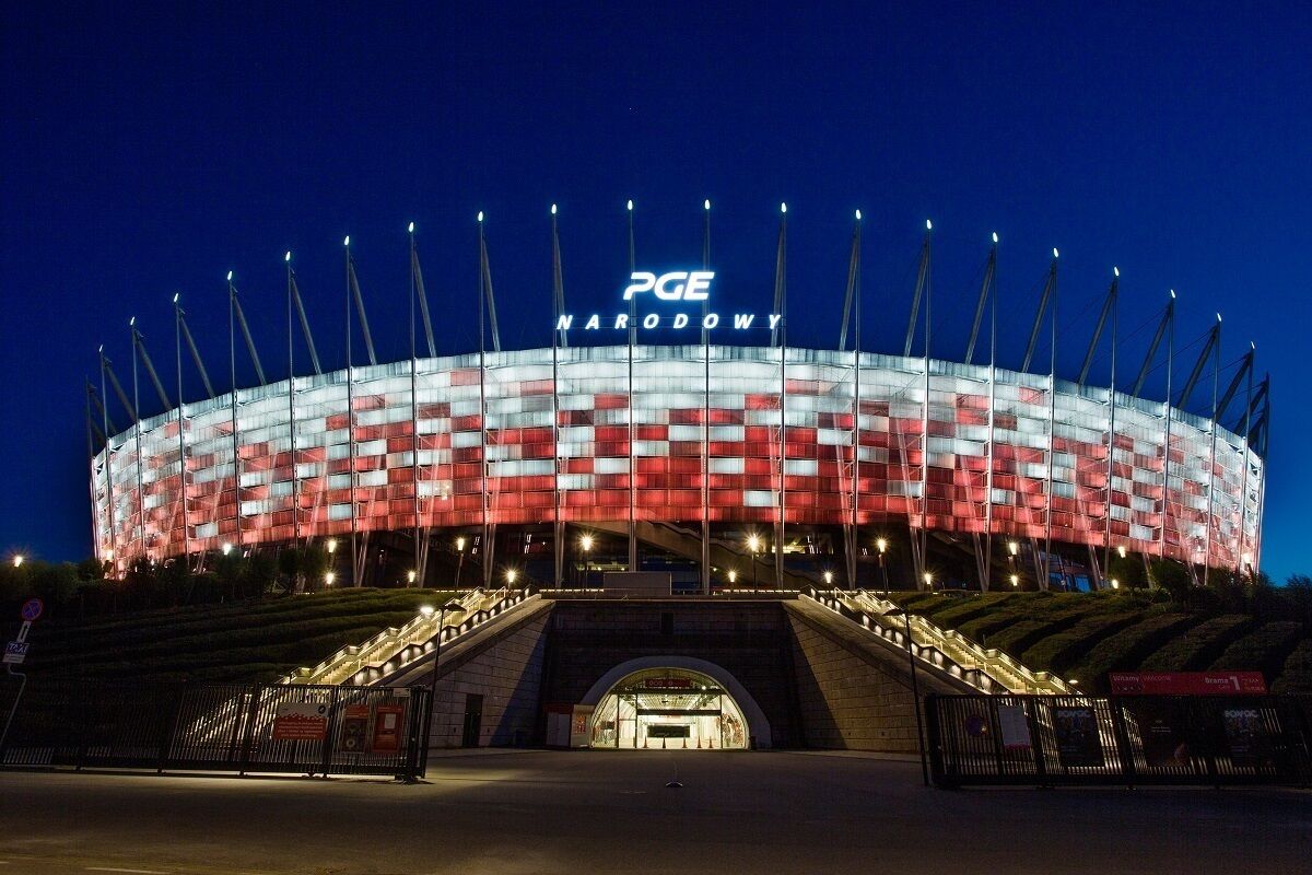 A stadium with a distinctive red and white checkered facade, featuring the text "PGE NARODOWY" prominently.