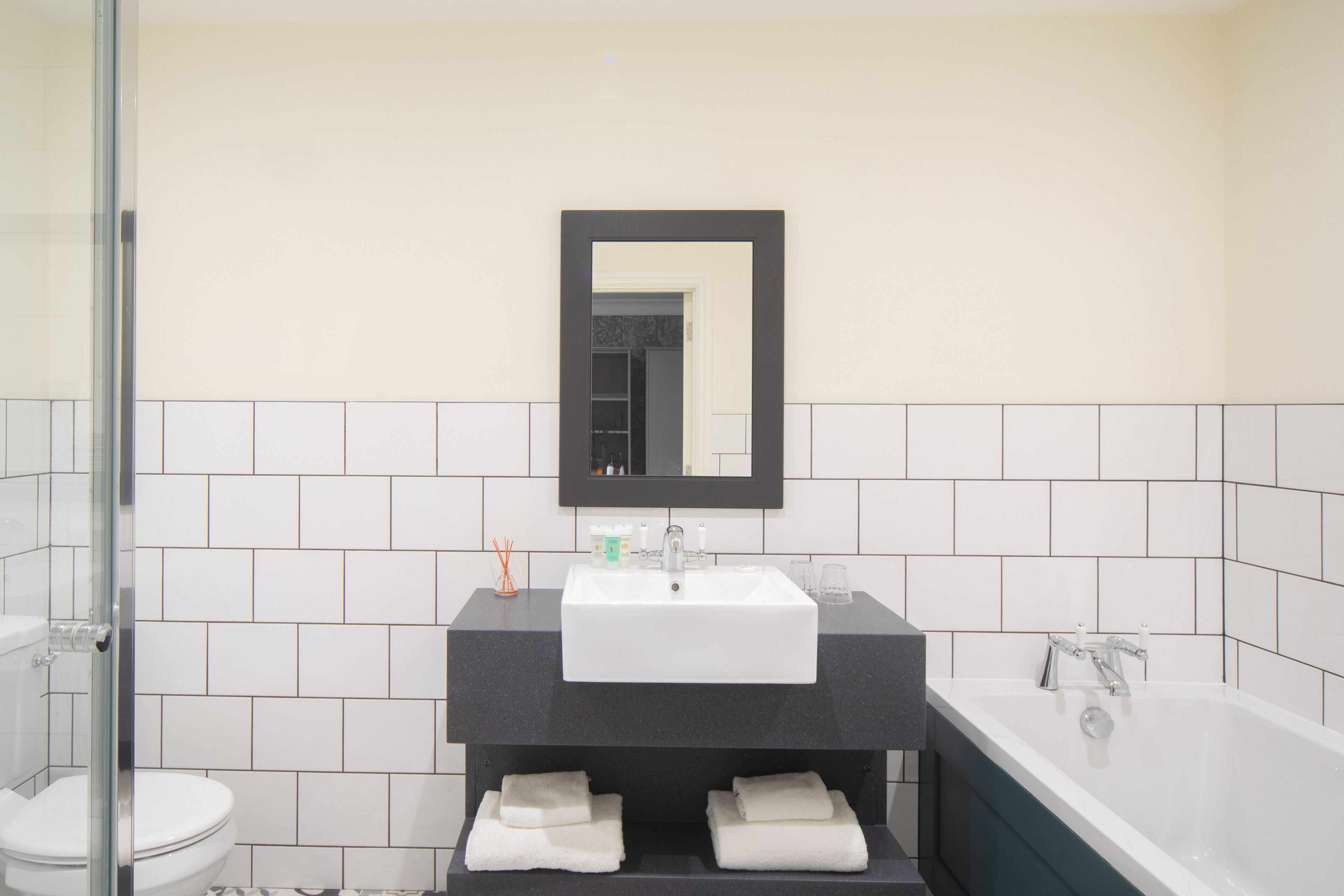 A bathroom with a white sink, a mirror above it, and a bathtub.