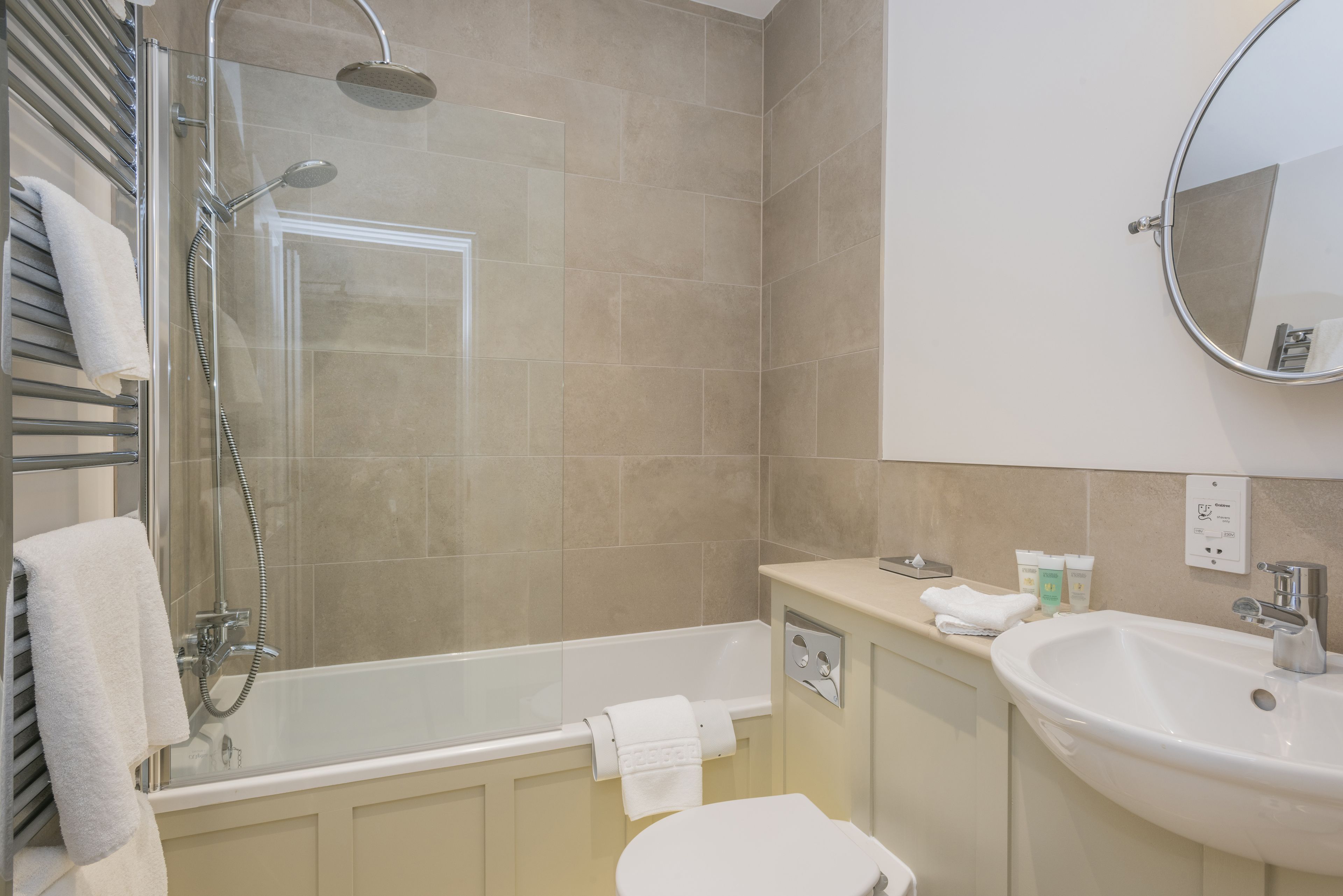 A modern bathroom with a glass-enclosed shower, a bathtub, a toilet, a sink, and a mirror.