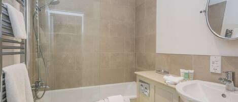 A modern bathroom with a glass-enclosed shower, a bathtub, a toilet, a sink, and a mirror.
