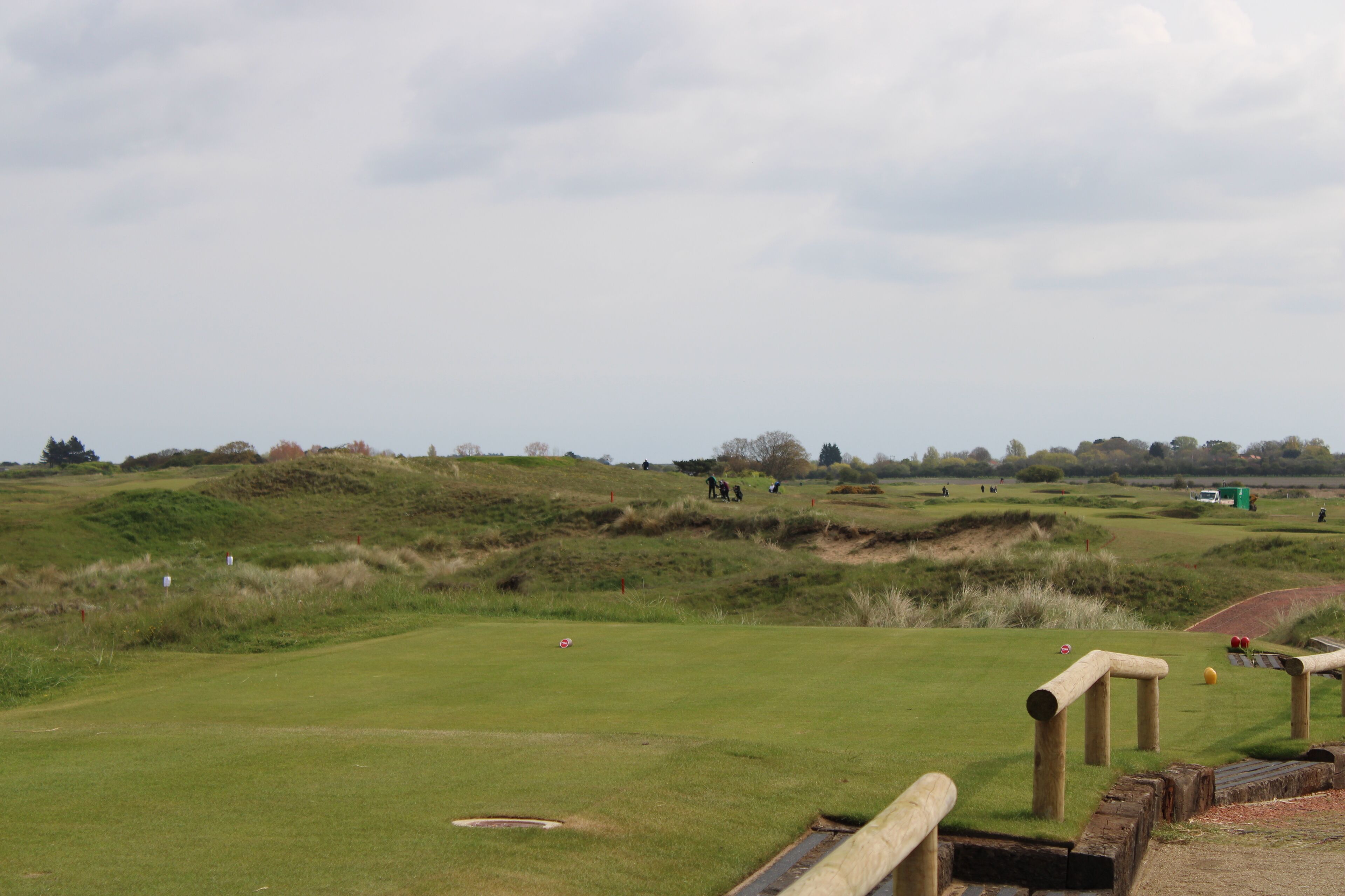 A golf course with a well-maintained green, sand bunkers, and wooden fences.
