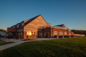 A large, modern building with a prominent sloped roof, large windows, and a covered outdoor area. - Heacham Manor Hotel (King's Lynn)