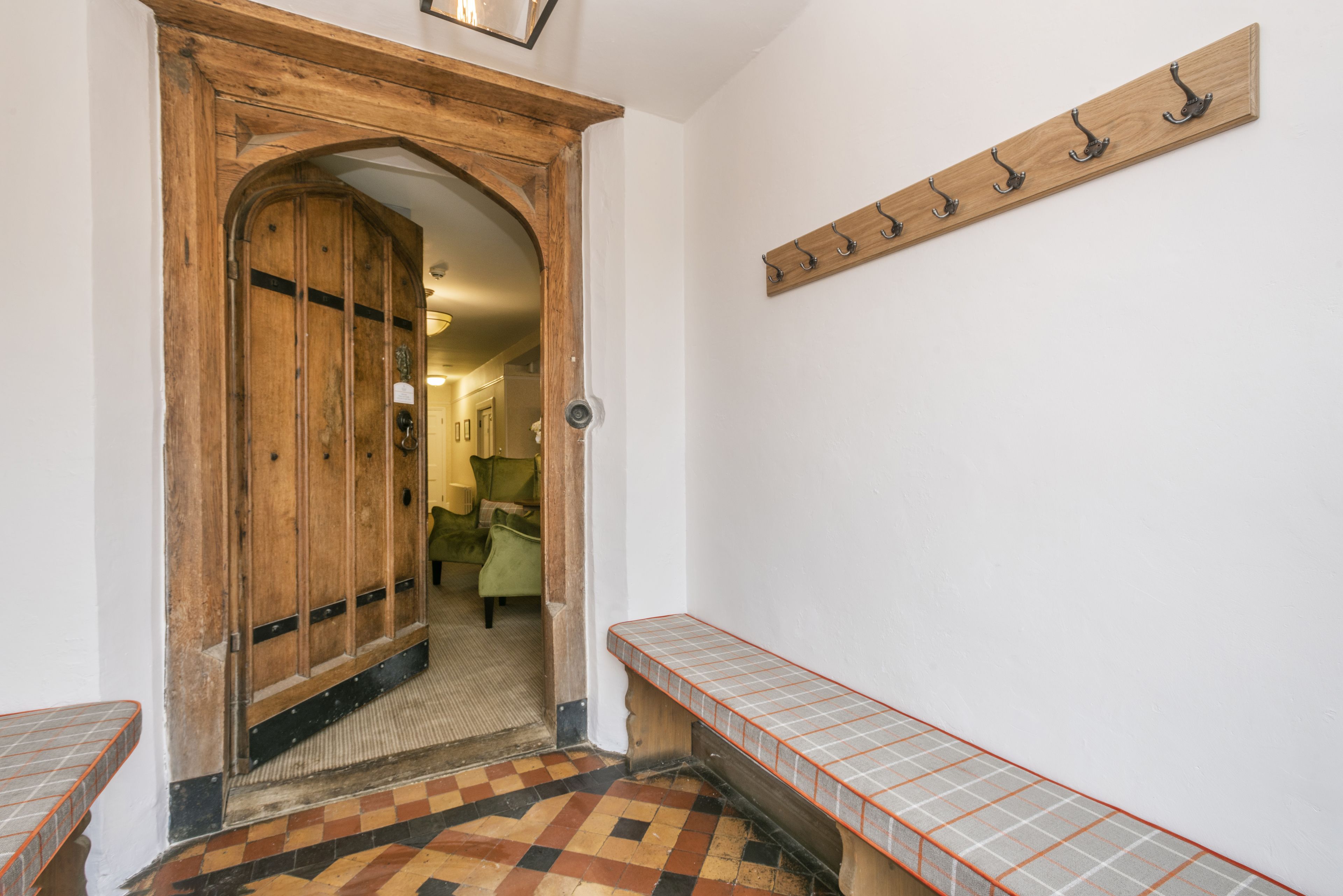 A hallway with a wooden door, a bench, and a coat rack.